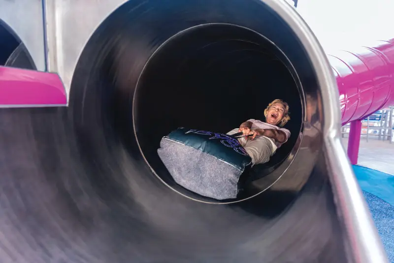 HM, Harmony of the Seas, Ultimate Abyss slides, senior woman, boomer, grandmother, riding down slide toward exit, hanging on to mat, POV in front of slide, laughing, fun, excitement, action,

NOTE: NO TV Broadcast for this still image.